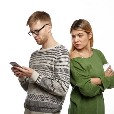 suspicious distrustful young blonde female green top standing her bearded boyfriend looking his shoulder spying him while he is typing message using mobile phone 344912 508