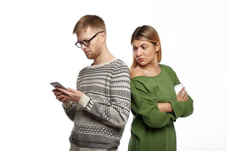 suspicious distrustful young blonde female green top standing her bearded boyfriend looking his shoulder spying him while he is typing message using mobile phone 344912 508
